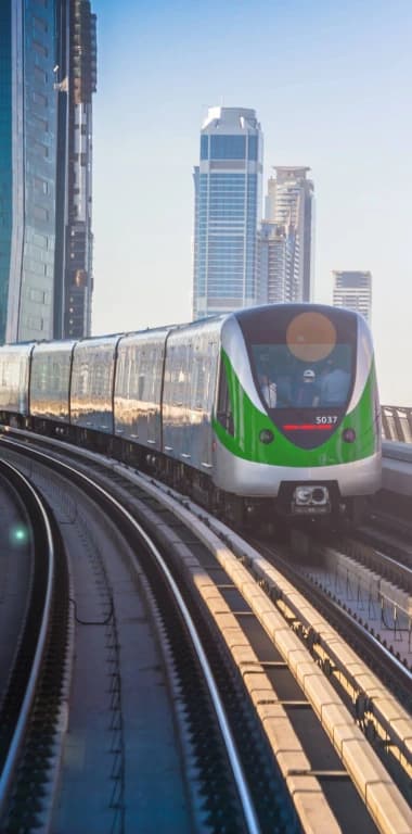 A metro train on elevated track against a city skyline
